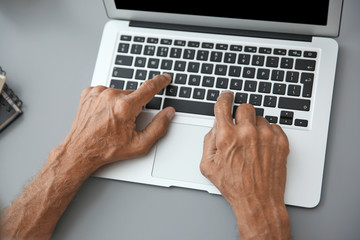 Hands of senior man typing on laptop