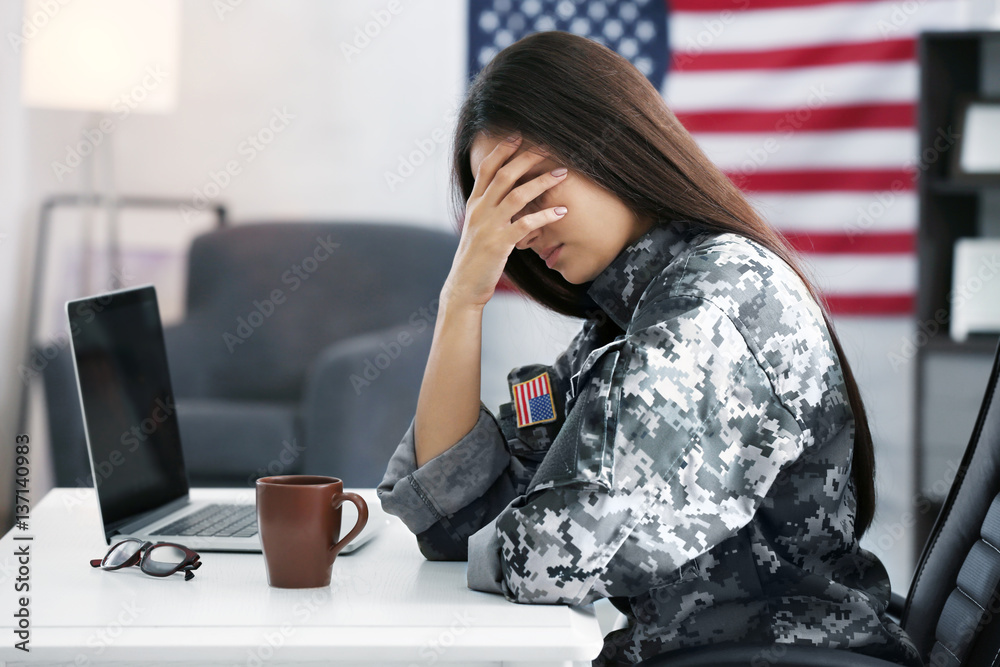 Poster Pretty female soldier working with laptop while sitting at table in headquarters building