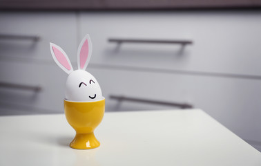 Easter egg with paper ears on table against blurred background