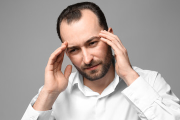 Handsome man suffering from headache, on color background