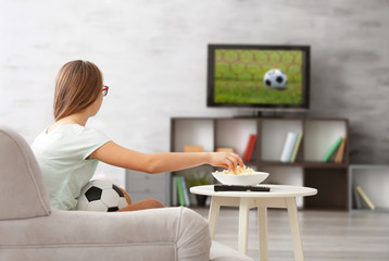 Obraz na płótnie Canvas Pretty teenager watching football match on TV at home