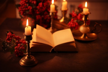 Open Bible, candle and mistletoe branch on table