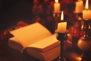 Closeup view of burning candle with blurred Bible on background