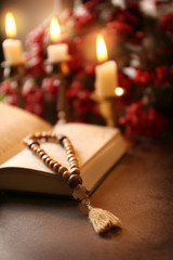 Open Bible and wooden rosary beads on table