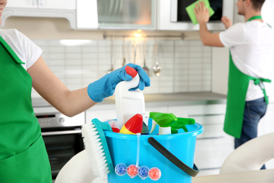 Woman taking cleanser from bucket with detergents, closeup