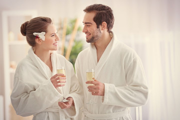Young happy couple drinking champagne in spa salon