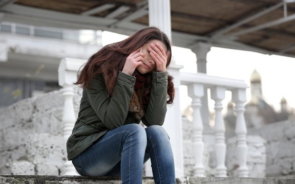 Depressed young woman sitting on stairs - Powered by Adobe