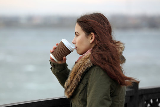 Depressed Young Woman Drinking Coffee On Pier