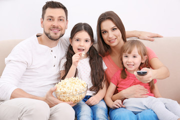 Happy family watching TV on sofa at home