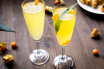 cocktail with physalis in glass on wooden background