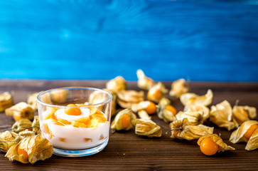 yogurt with physalis on wooden background