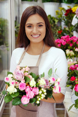 Pretty young florist with bouquet in flower shop