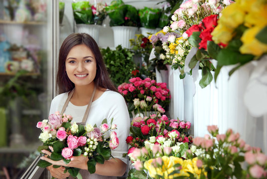 Pretty young florist with bouquet in flower shop