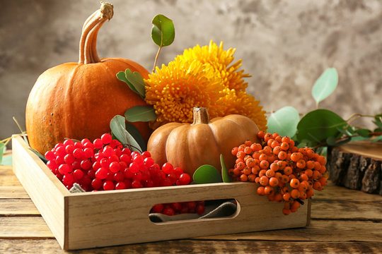 Pumpkins, rowan and viburnum in wooden box on table on blurred background