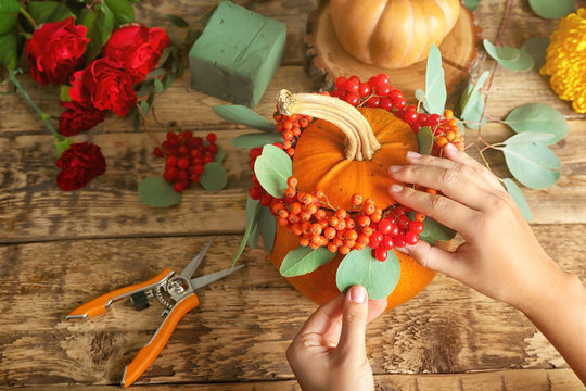 Florist at work. Composition with pumpkin, rowan and viburnum on wooden background