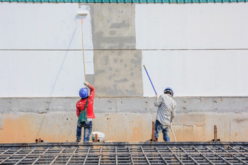 Young painter with blue cap and gloves painting a wall with paint roller; copy space