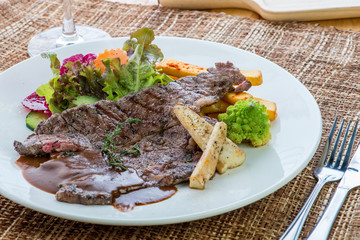 Gourmet grilled steak flavoured with basil beef steak with roasted pumpkin and fresh green herb salad