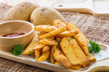 Tasty french fries on cutting board with ketchup, on wooden table background