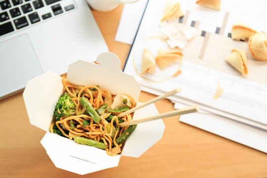 Chinese Food Box On The Office Desk. Eating At The Office. Overtime Work Concept.