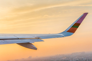 Obraz premium The wing aircraft in altitude during flight over the city with Evening sky