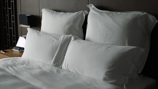 A double bed with white sheets in a hotel room-Dan