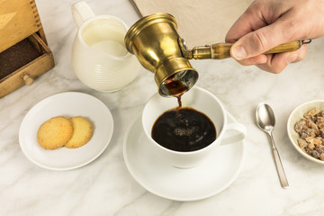 Coffee poured into cup, with milk jar and cane sugar