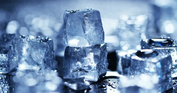 Macro shot of pure water ice cubes that melt in slow motion on blue background. Concept: pure mountain spring water, ice, cocktails, fresh and frozen products.
