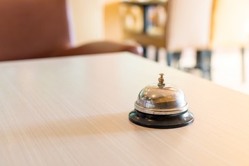 Concept hotel : old silver call bell on the wooden table,
Hotel service bell on a table.