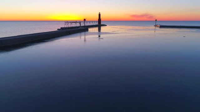 Scenic aerial flyby of Lake Michigan lighthouse, harbor at twilight.
