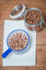 Кукурузные шоколадные шарики в чашке с молоком на завтрак на деревянном столе.