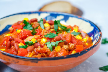Chili con carne in a clay bowl on a concrete background. Traditional Mexican cuisine