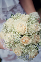 A bouquet of white roses in hands of bride