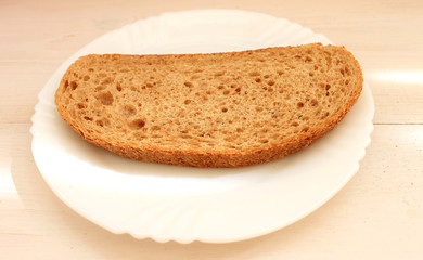Slice of dark bread with bran on the white plate