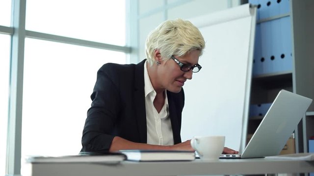 Who&rsquo;s a good girl? I&rsquo;m a good girl!/Business woman in the workplace. She wrote a letter on the laptop. After sending it, smiled and performed a little dance right on the chair
