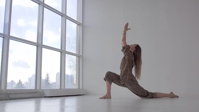 Caucasian woman practicing lunges in white studio