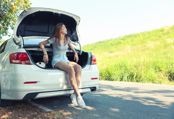 Relaxed happy woman sit at car rear on summer road trip travel.