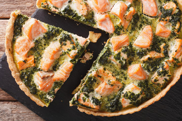 Savory food: sliced tart with salmon, spinach and cream close-up. Horizontal top view
