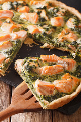 Sliced Quiche with salmon, spinach and cream close-up. vertical