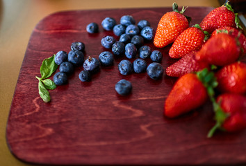 Fresh strawberries and blueberries on wooden cutting board. Concept of healthy eating.