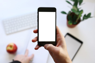 smart phone in hand on the background of working business environment