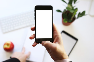 smart phone in hand on the background of working business environment