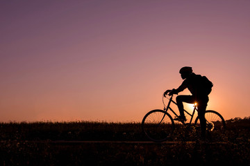 silhouette of person on bicycle in natural sunset