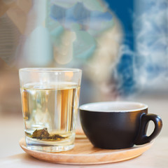 Close up coffee cup with steam on table in cafe.