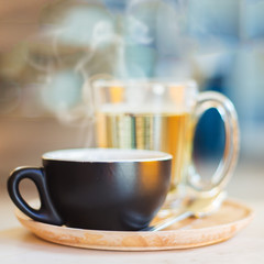 Close up coffee cup with steam on table in cafe.