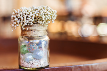 Dried flowers in glass bottle on wood table decorations in cafe.