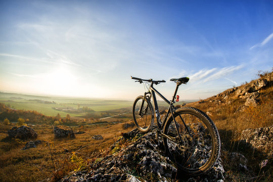 Mountain bicycle on hill under blue sky with clouds. © Aleksey