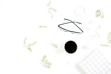 Coffee cup, notebook, glasses, green branches and female accessories on white background. Flat lay, top view