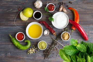  Sauces, spice, herbs, oil, condiments, seeds,cream, vegetables, lime, peppers, dried herbs, bowls, spoon on rustic wooden table. Selective focus.