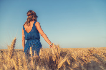 Girl enjoying in a wheat-field with arms wide open.