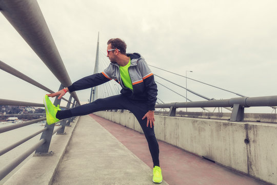 Urban jogger stretching / exercising on the bridge.